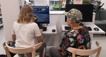 En flicka och en pojke sitter vid bibliotekets datorer.